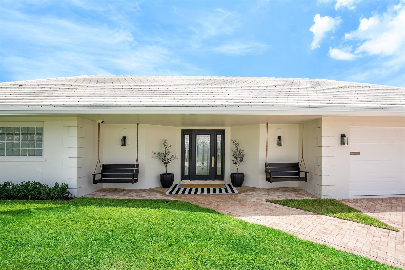 A white single-story house with a tiled roof, palm trees, and a paved driveway — 1332 SW Tamarind Way, Boca Raton FL 33486, BOCA RATON, FL