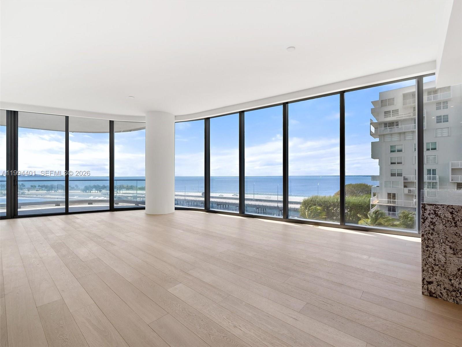 An empty room features light wood flooring, floor-to-ceiling windows, and a view of the ocean — 175 SE 25th Rd # 502, Miami FL 33129, MIAMI, FL