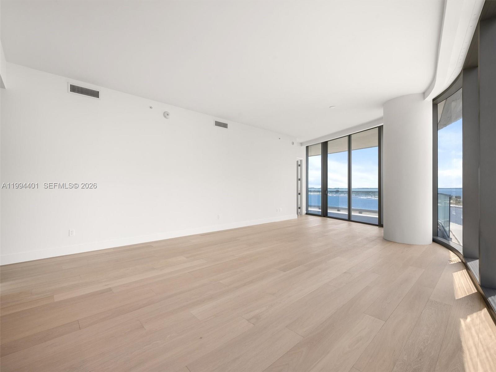 An empty room features light wood flooring, white walls, and floor-to-ceiling windows overlooking water — 175 SE 25th Rd # 502, Miami FL 33129, MIAMI, FL