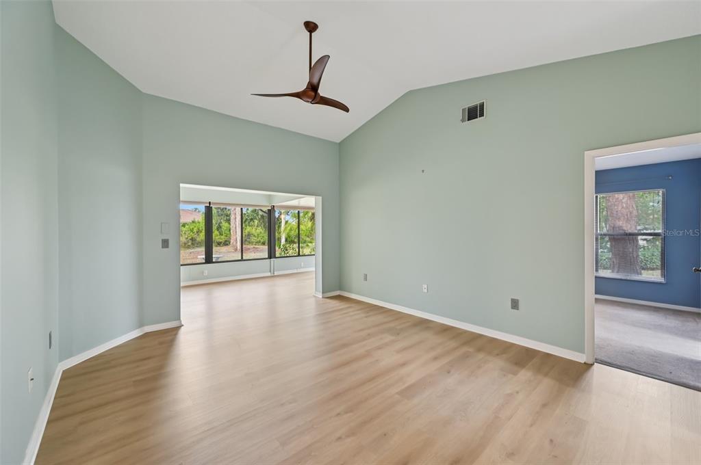 A spacious living room with light green walls, wood-look flooring, and a vaulted ceiling — 227 SOUTHAMPTON DRIVE UNIT 289, VENICE, FL