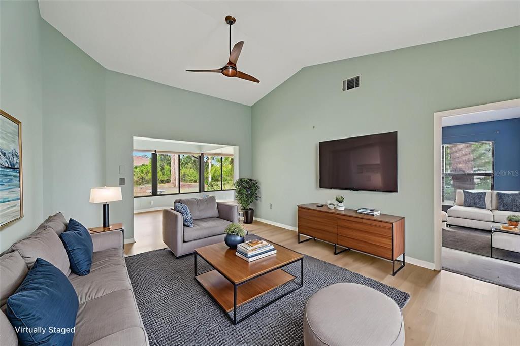 A living room with light green walls, a vaulted ceiling, and wood-look flooring — 227 SOUTHAMPTON DRIVE UNIT 289, VENICE, FL