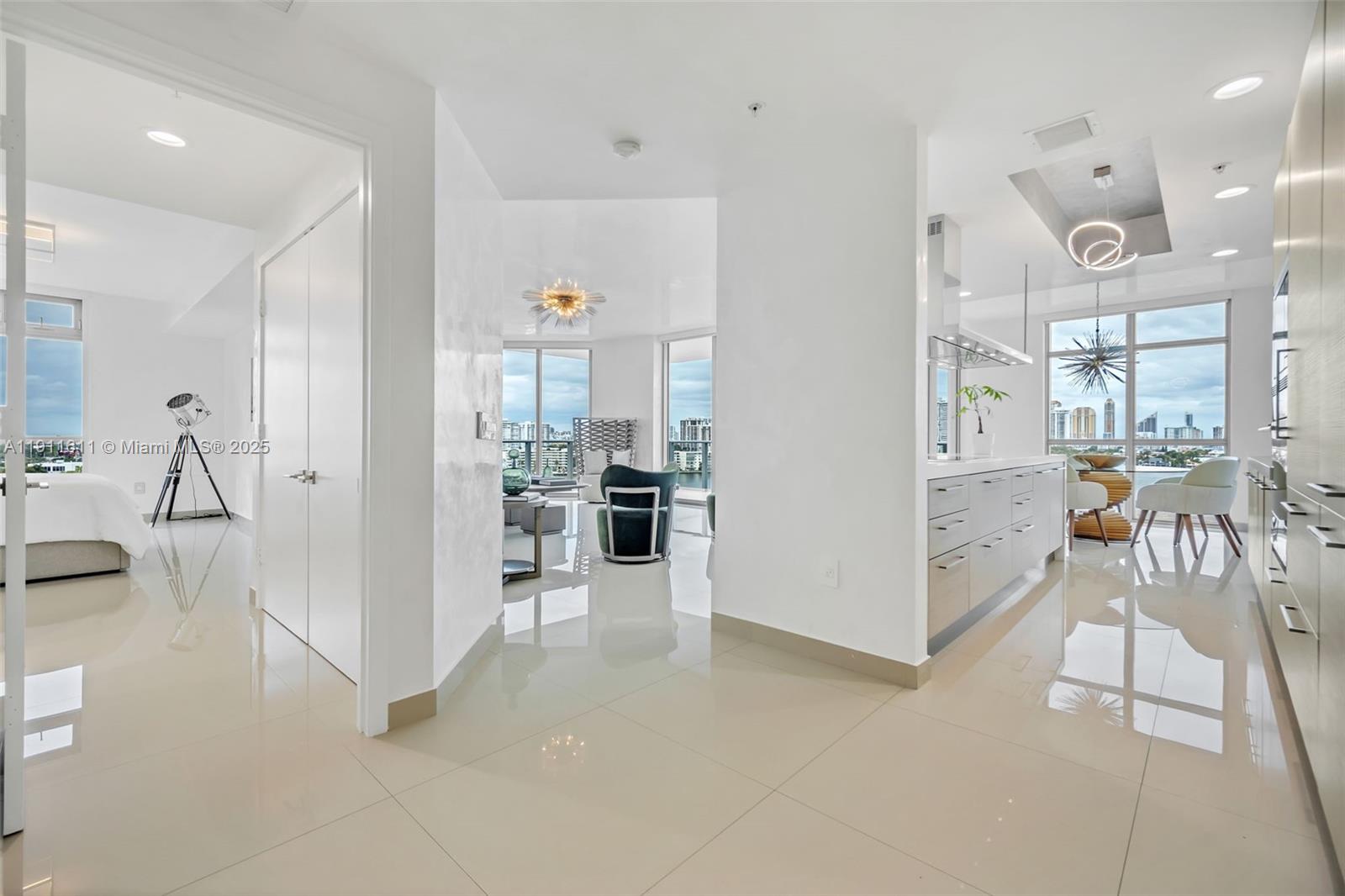 A bright, modern apartment interior features white tile floors, a kitchen, and a living area — 17301 Biscayne Blvd # 910, North Miami Beach FL 33160, NORTH MIAMI BEACH, FL