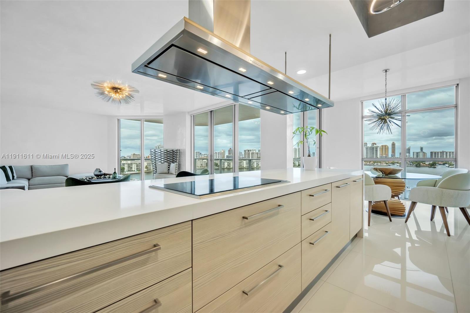A modern kitchen features light wood cabinetry, a white countertop, and a large range hood — 17301 Biscayne Blvd # 910, North Miami Beach FL 33160, NORTH MIAMI BEACH, FL