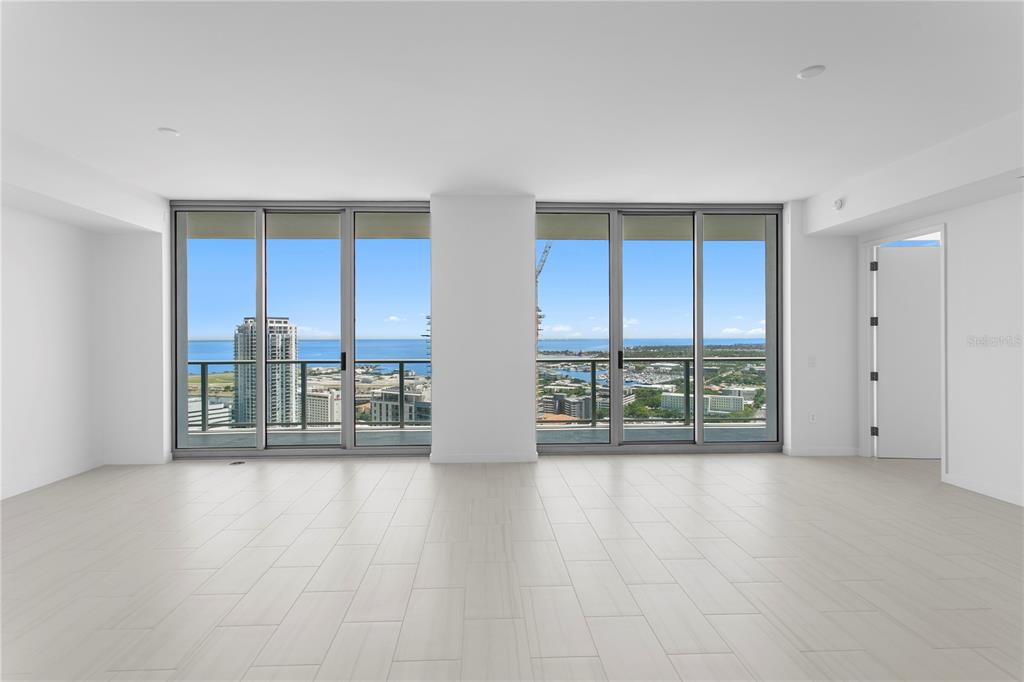 An empty room with light tile flooring and floor-to-ceiling windows overlooking a coastal city — 400 CENTRAL AVENUE UNIT 3005, ST PETERSBURG, FL