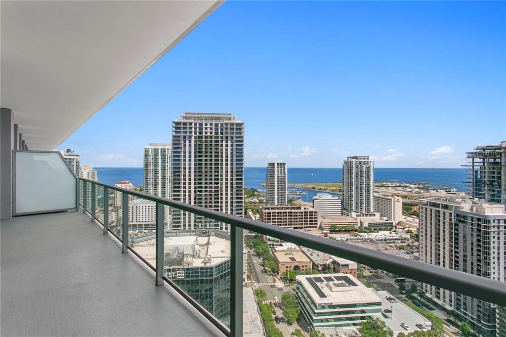 A high-rise balcony overlooks a city skyline and the ocean on a sunny day — 400 CENTRAL AVENUE UNIT 3005, ST PETERSBURG, FL