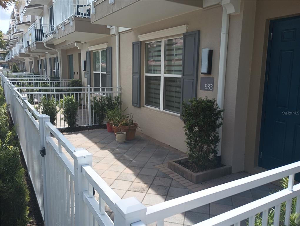 A paved patio area sits in front of a townhouse entrance with a white fence — 933 BRUTUS TERRACE, LAKE MARY, FL