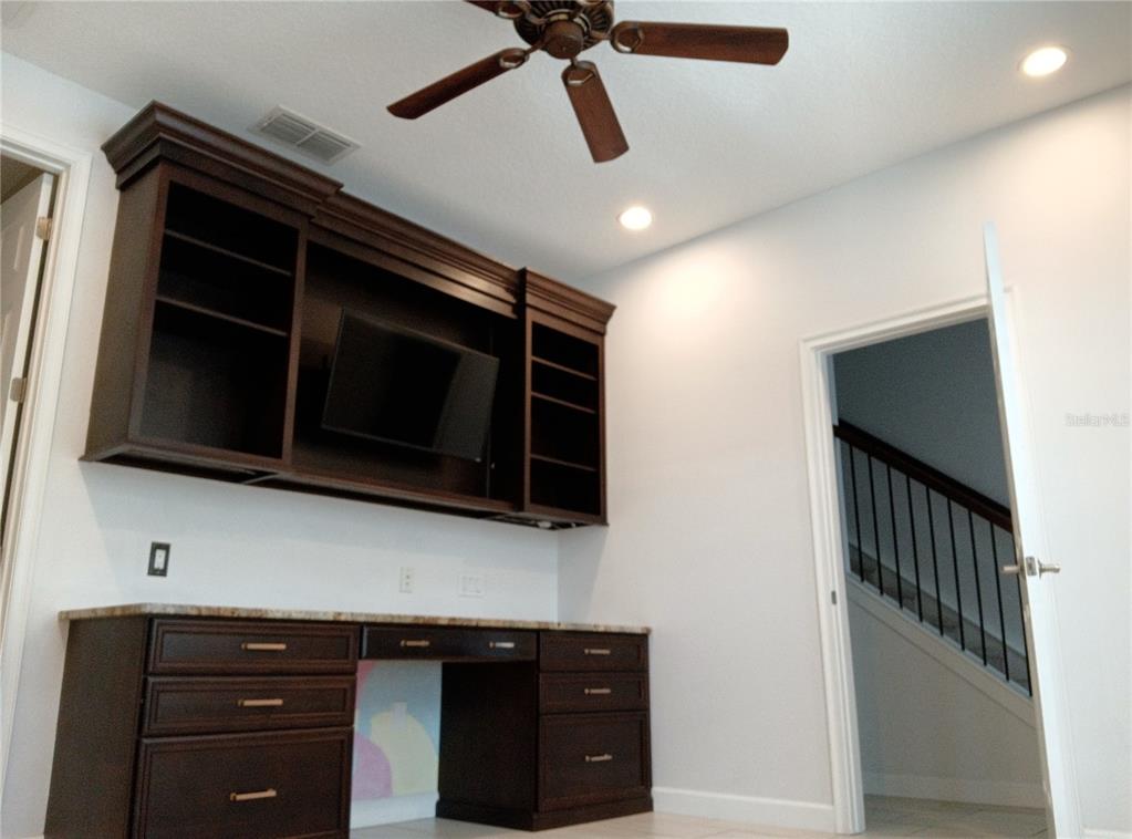 A home office features dark wood built-in cabinetry, a desk with drawers, and a ceiling fan — 933 BRUTUS TERRACE, LAKE MARY, FL