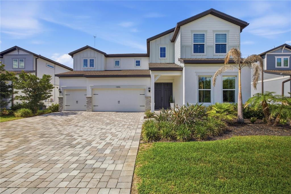 A two-story suburban house with a paved driveway, three-car garage, and light-colored exterior siding — 13816 SHARP HAWK DRIVE, RIVERVIEW, FL