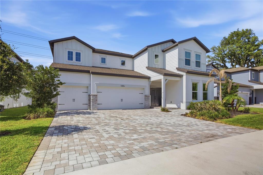 A two-story house with a three-car garage and a paved driveway under a blue sky — 13816 SHARP HAWK DRIVE, RIVERVIEW, FL