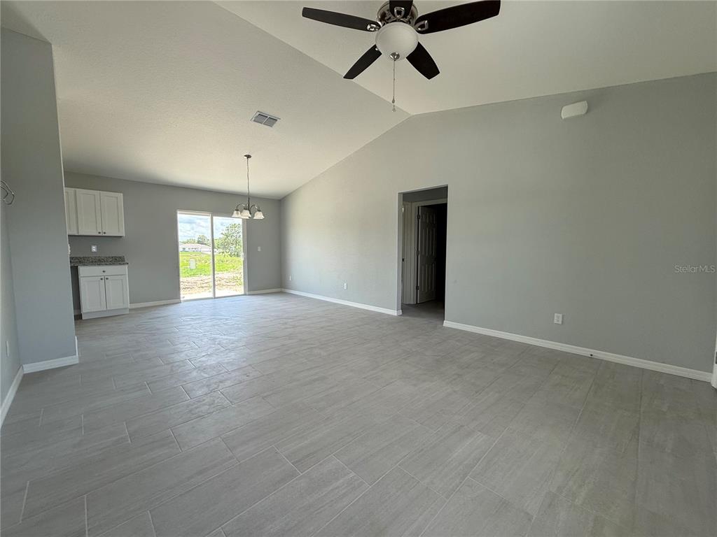 An open-concept living and dining area features gray tile flooring, light gray walls, and a ceiling fan — 13108 SW 104TH LANE, DUNNELLON, FL