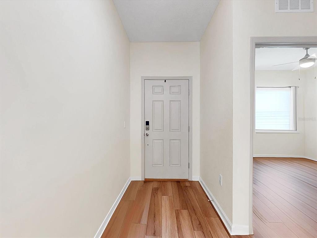A light-colored entryway features wood-look flooring and a door leading to an adjacent room — 749 ORCHID GROVE BOULEVARD, DAVENPORT, FL