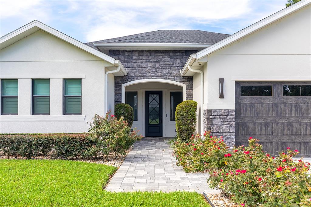 A single-story house exterior features a stone-accented entryway, a paved walkway, and a garage — 14941 GREEN VALLEY BOULEVARD, CLERMONT, FL