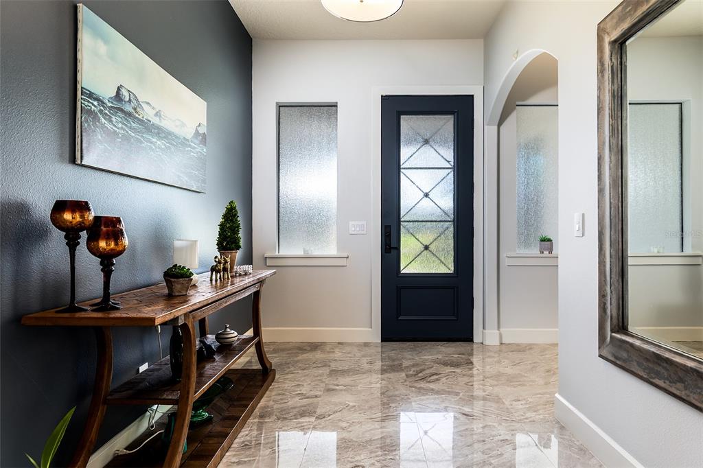 An entryway features a dark blue front door, a wooden console table, and marble flooring — 14941 GREEN VALLEY BOULEVARD, CLERMONT, FL
