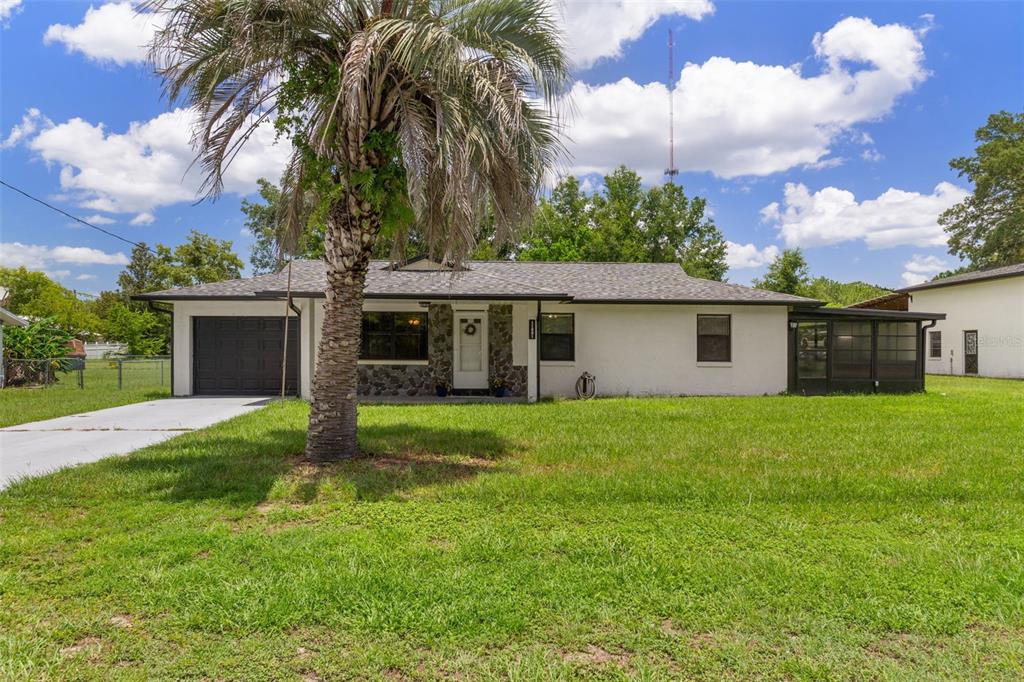 A single-story house with a white exterior, stone accents, a palm tree, and a garage — 11891 SE 84TH AVENUE, BELLEVIEW, FL