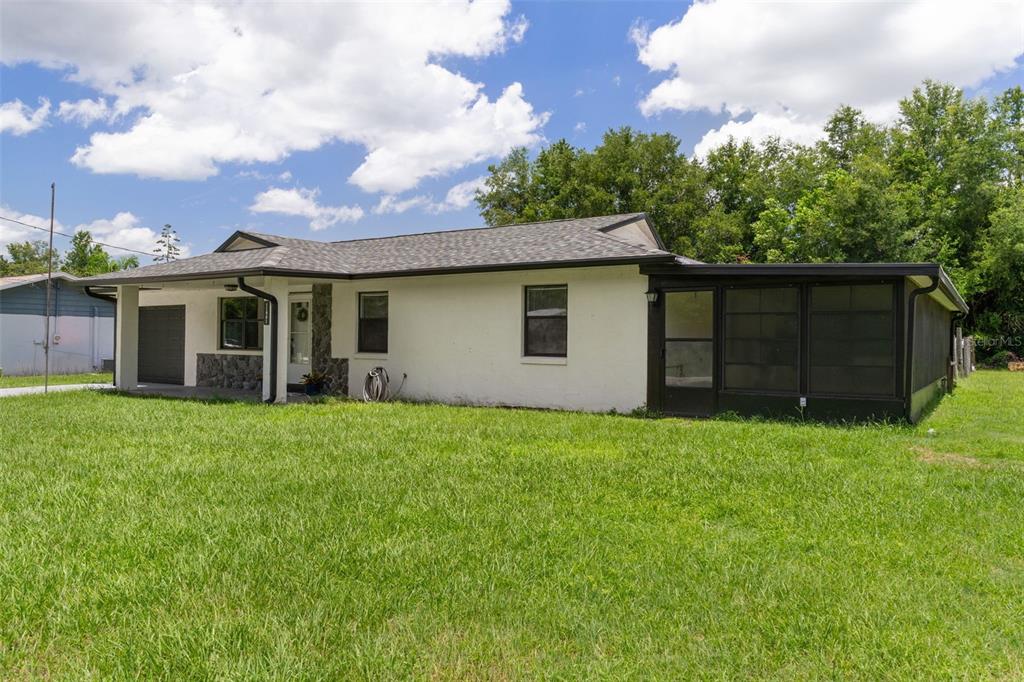A single-story white house with a dark roof and a screened-in porch on the side — 11891 SE 84TH AVENUE, BELLEVIEW, FL