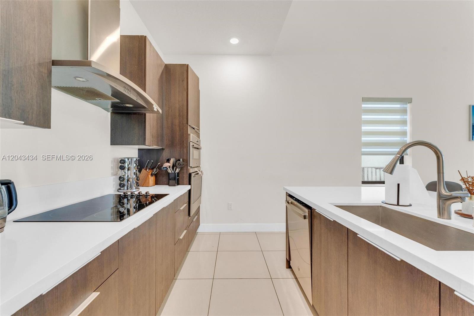 A modern kitchen features dark wood cabinetry, white countertops, stainless steel appliances, and tile flooring — 8822 NW 161st Ter, Miami Lakes FL 33018, MIAMI LAKES, FL