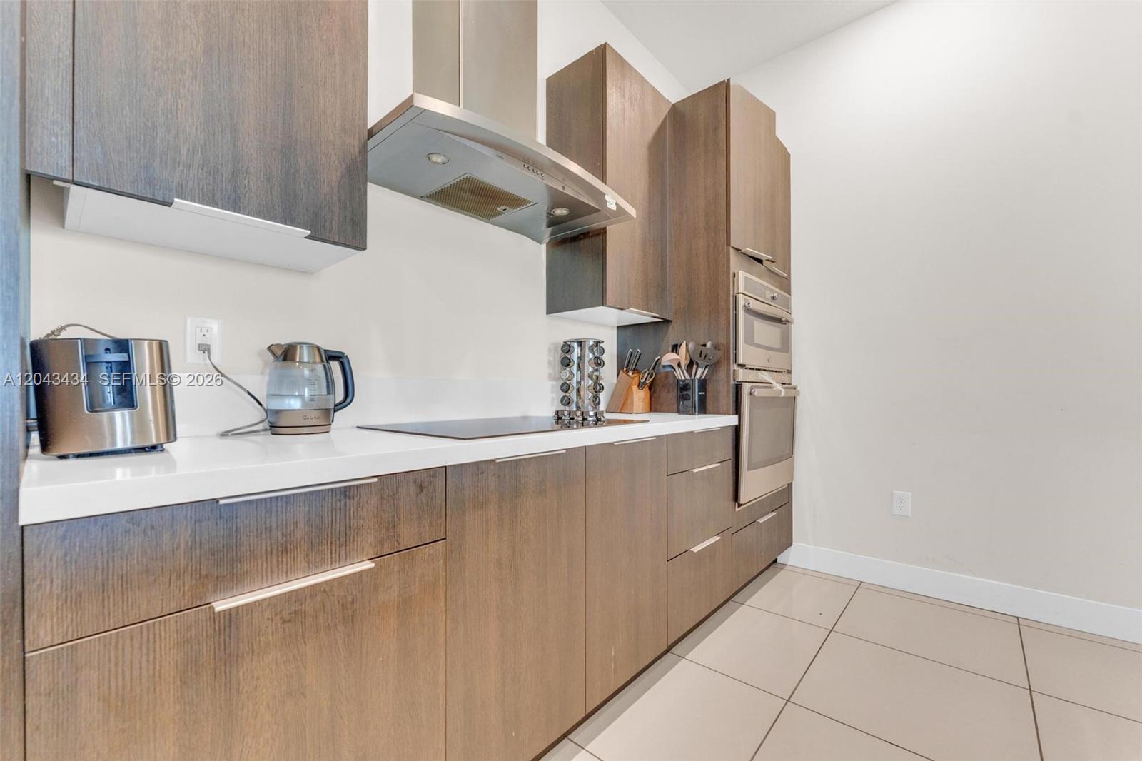 A modern kitchen features dark wood cabinetry, stainless steel appliances, and white countertops — 8822 NW 161st Ter, Miami Lakes FL 33018, MIAMI LAKES, FL