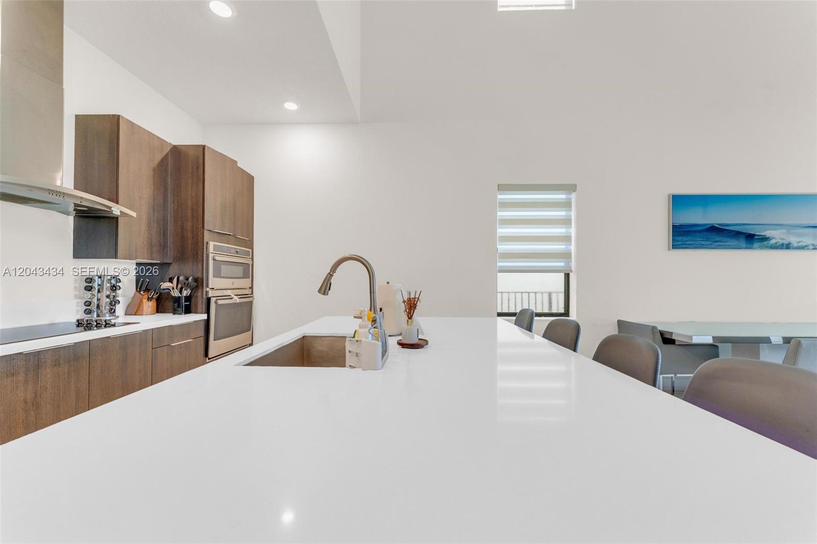 A modern kitchen features a large white island, dark wood cabinetry, and stainless steel appliances — 8822 NW 161st Ter, Miami Lakes FL 33018, MIAMI LAKES, FL