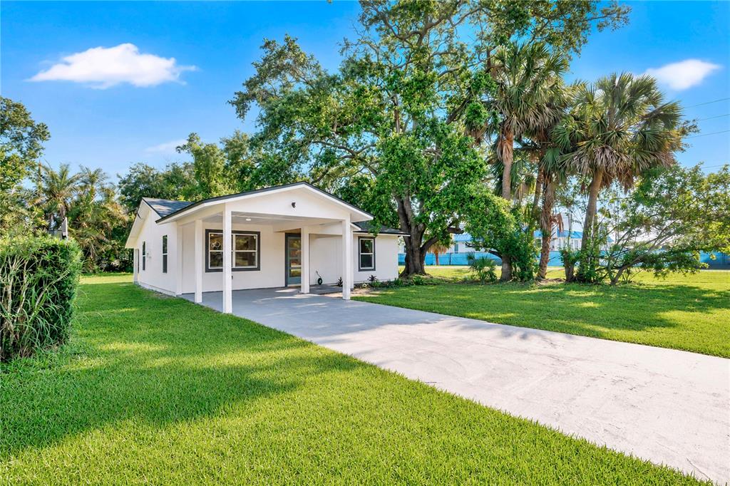 A white single-story house with a front carport sits on a grassy lot with trees — 483 PENNSYLVANIA AVENUE, WINTER GARDEN, FL