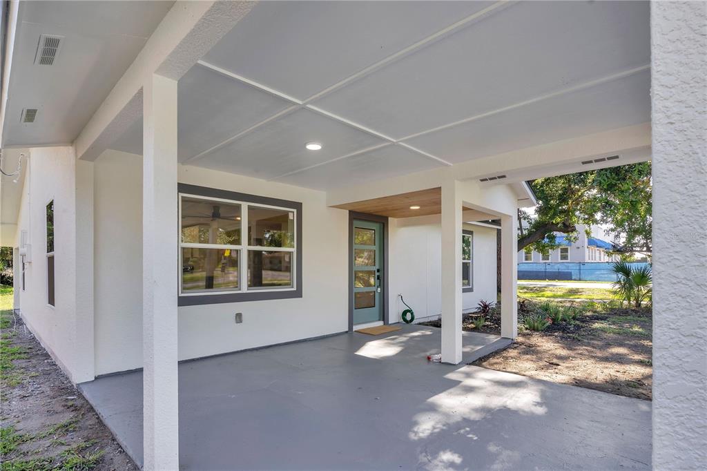 A covered concrete porch features white support columns, a teal front door, and recessed lighting — 483 PENNSYLVANIA AVENUE, WINTER GARDEN, FL