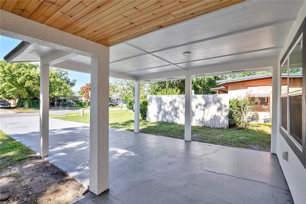 A covered concrete carport features a wood-paneled ceiling and white support columns — 483 PENNSYLVANIA AVENUE, WINTER GARDEN, FL