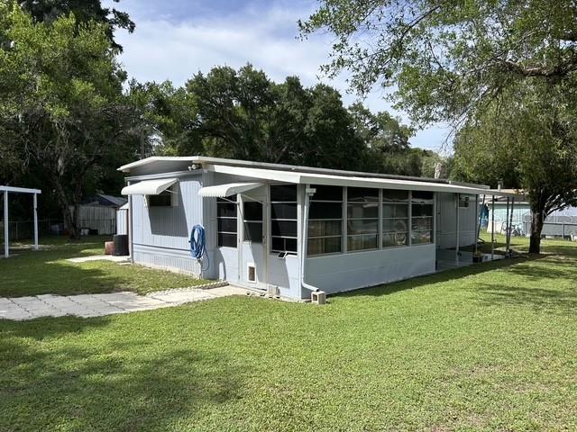 A light blue mobile home with a screened-in porch sits on a grassy lot — 3399 SE 93RD PLACE, OCALA, FL