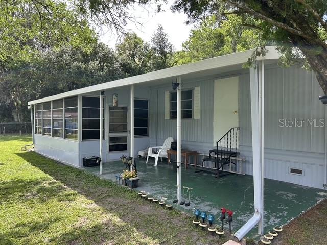 A mobile home features a covered patio with a green floor and a screened enclosure — 3399 SE 93RD PLACE, OCALA, FL