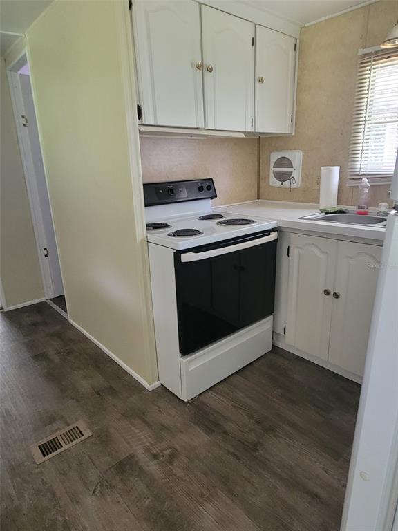 A kitchen features white cabinets, a black electric stove, and wood-look flooring — 3399 SE 93RD PLACE, OCALA, FL