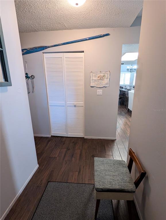A hallway with wood-look flooring, a louvered closet door, and a small upholstered chair — 2001 GROVELAND ROAD, PALM HARBOR, FL