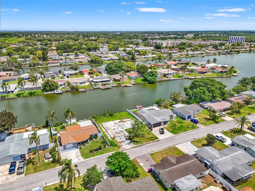 An aerial view shows a residential neighborhood with houses along a canal and a vacant lot — 4101 BADEN DRIVE, HOLIDAY, FL
