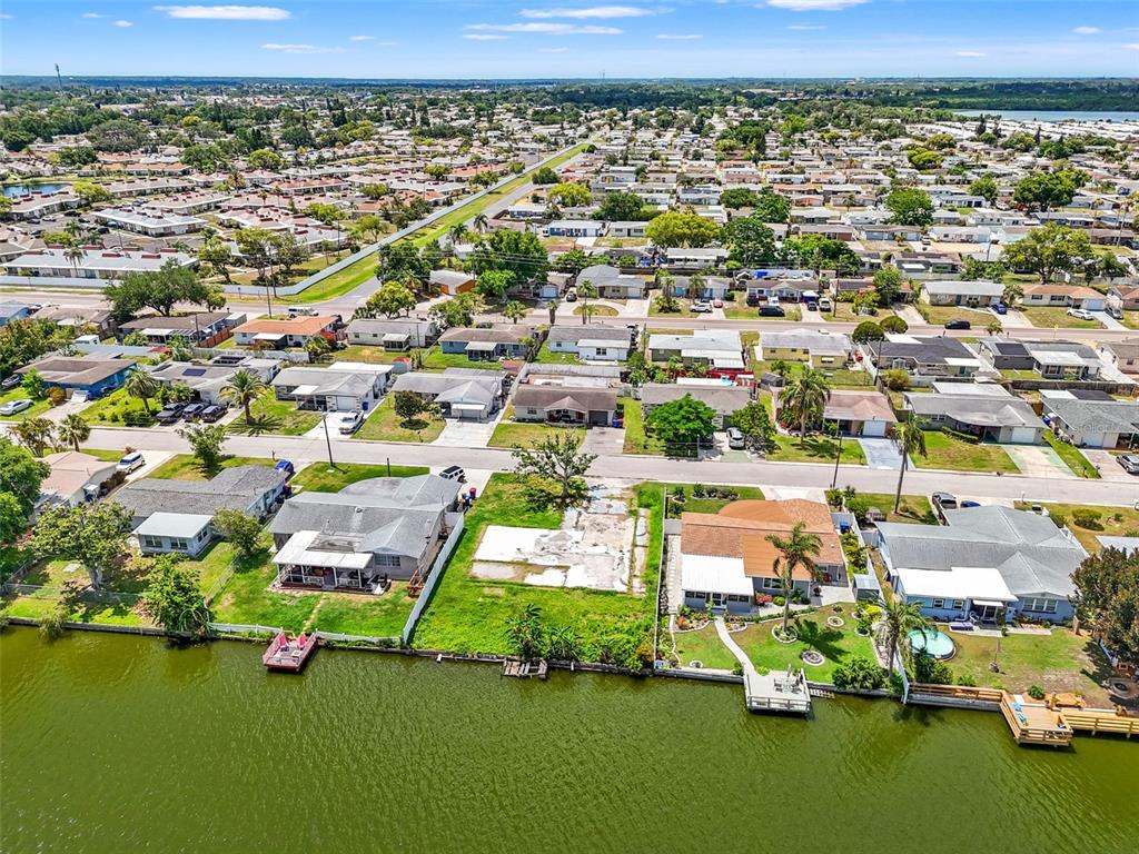 An aerial view shows a vacant waterfront lot situated between two houses along a canal — 4101 BADEN DRIVE, HOLIDAY, FL