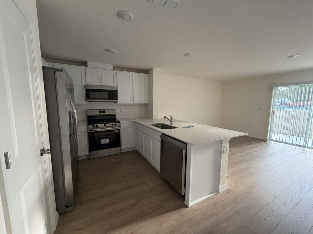 A kitchen with white cabinets, stainless steel appliances, and a peninsula island with a sink — 1814 LINDENS STREET, KISSIMMEE, FL