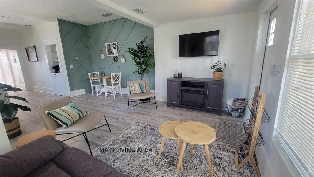 A living room features a green accent wall, light wood flooring, and a television console — 541 MARGARET COURT, ORLANDO, FL