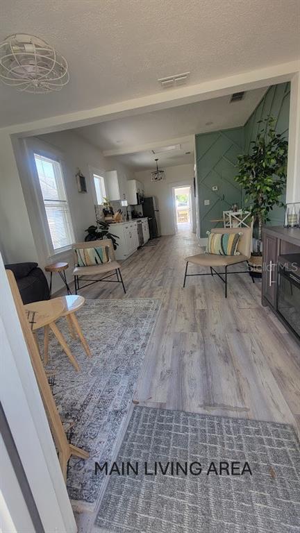 A living room with wood-look flooring leads into a kitchen with white cabinets — 541 MARGARET COURT, ORLANDO, FL