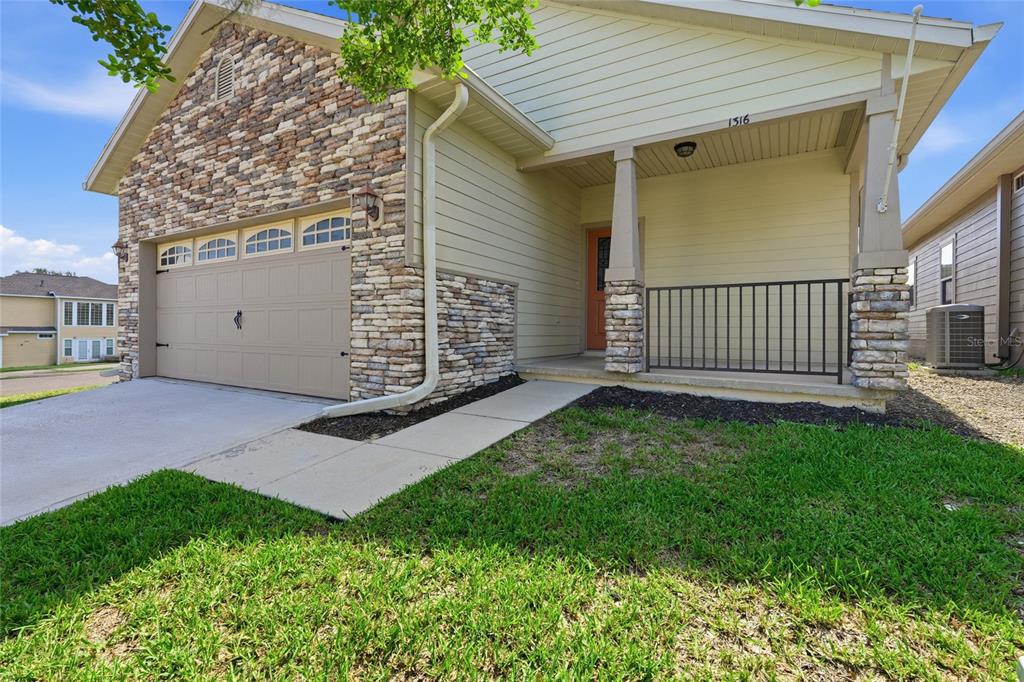 A single-story house exterior features a stone facade, a two-car garage, and a covered porch — 1316 NW 120TH WAY, GAINESVILLE, FL
