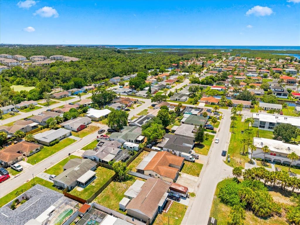 An aerial view shows a residential neighborhood with houses, streets, and trees near the coast — 6224 KELLER DRIVE, PORT RICHEY, FL