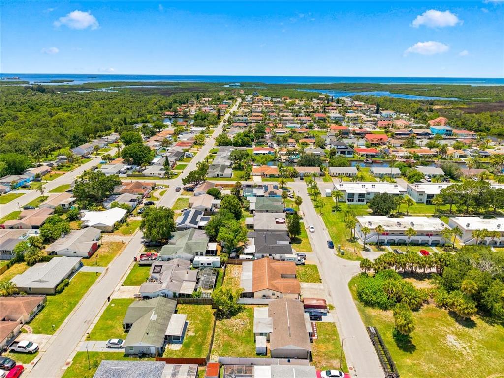 An aerial view shows a residential neighborhood with houses, streets, and a distant coastline — 6224 KELLER DRIVE, PORT RICHEY, FL