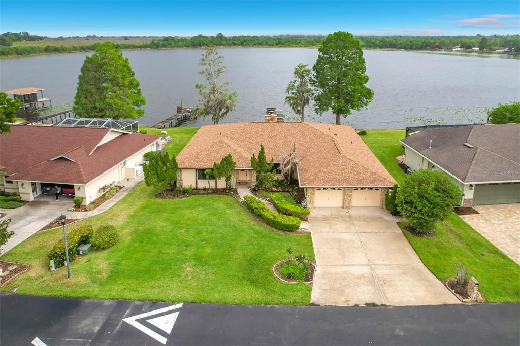 An aerial view of a single-story house with a tan roof, garage, and lakefront backyard — 247 S LAKE PANSY DRIVE, WINTER HAVEN, FL