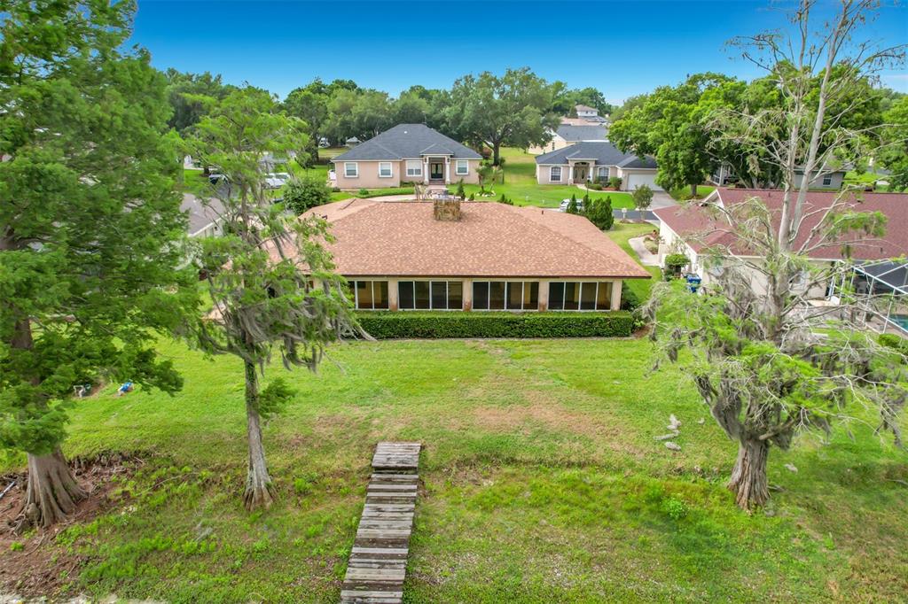 An aerial view of a single-story house with a large sunroom and a wooden walkway — 247 S LAKE PANSY DRIVE, WINTER HAVEN, FL
