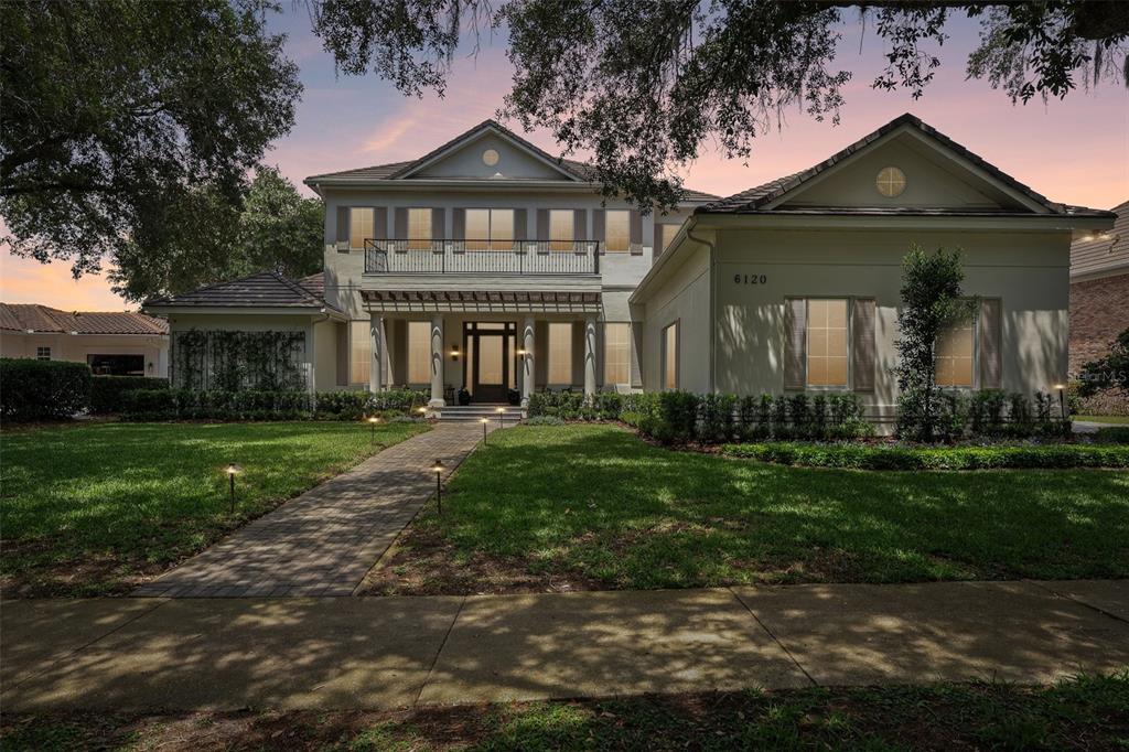 A two-story house with a paved walkway, a balcony, and a pergola over the entrance — 6120 GREATWATER DR, WINDERMERE, FL