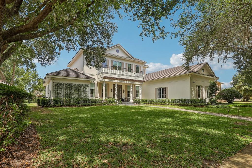 A two-story house with a white exterior, a balcony, and a large front lawn — 6120 GREATWATER DR, WINDERMERE, FL