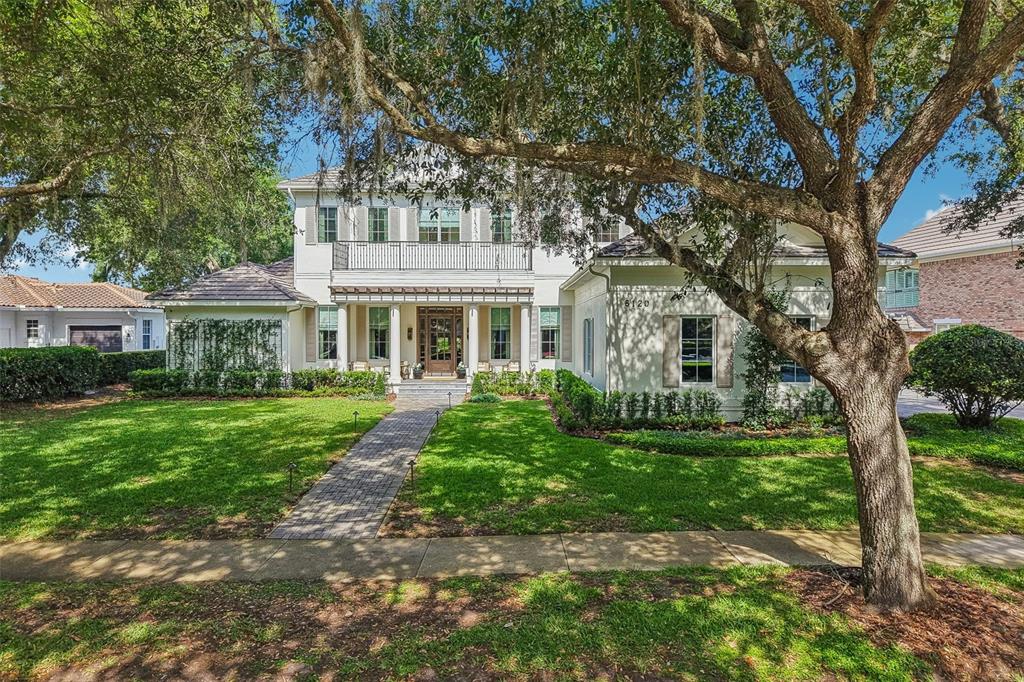 A two-story house with a brick walkway, white exterior, and a large oak tree — 6120 GREATWATER DR, WINDERMERE, FL