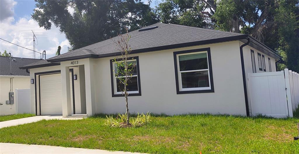 A single-story house with white stucco walls, dark trim, and a white vinyl fence — 4013 E CURTIS STREET, TAMPA, FL