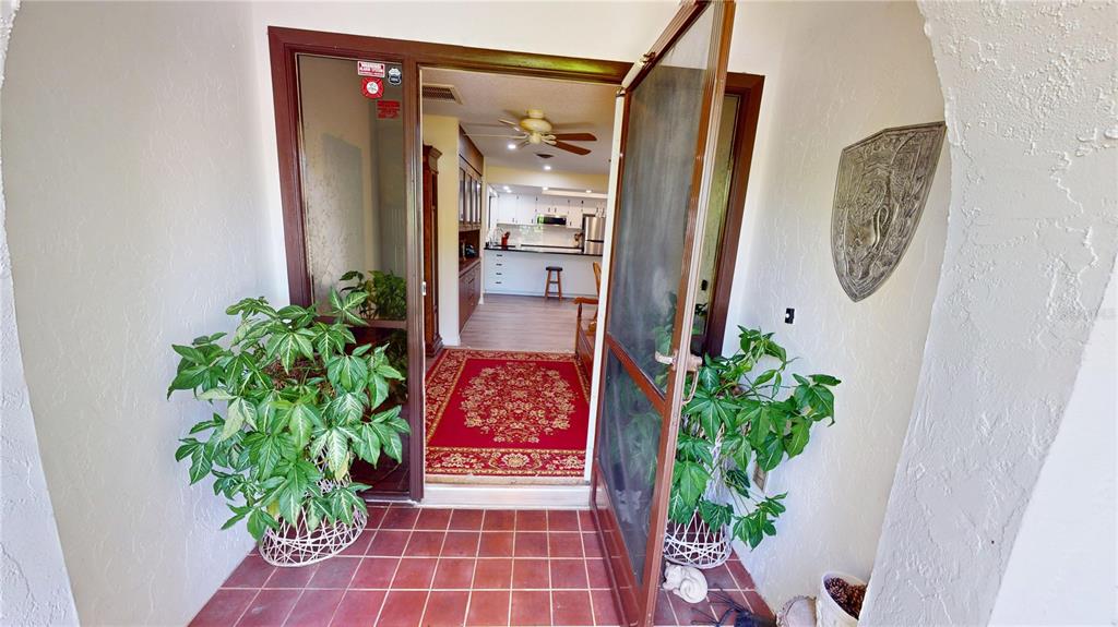 A view through an open doorway into a home with a red rug and kitchen — 18422 BURKHOLDER CIRCLE, PORT CHARLOTTE, FL