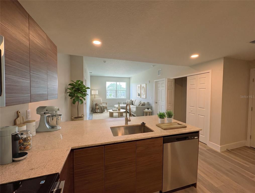 A kitchen with wood-grain cabinets and a light countertop overlooks a living room area — 4424 S TEXAS AVENUE UNIT 1-218, ORLANDO, FL