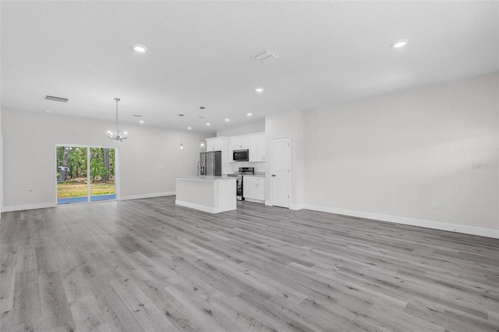 An open-concept kitchen and living area features light gray flooring, white cabinetry, and sliding doors — 1028 W CITRUS SPRINGS BOULEVARD, CITRUS SPRINGS, FL