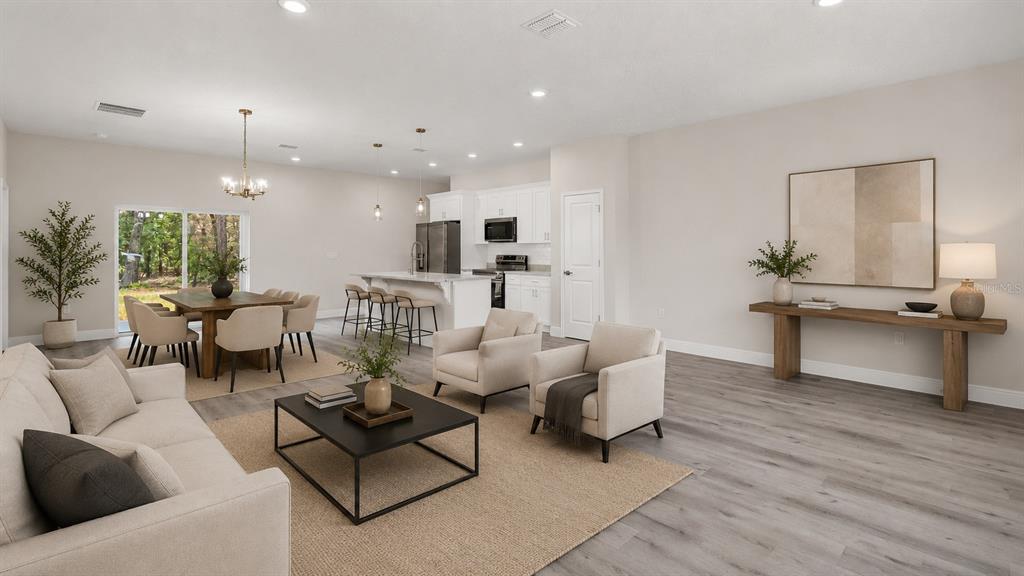 An open-concept living and dining area features light wood flooring, white cabinetry, and neutral furniture — 1028 W CITRUS SPRINGS BOULEVARD, CITRUS SPRINGS, FL