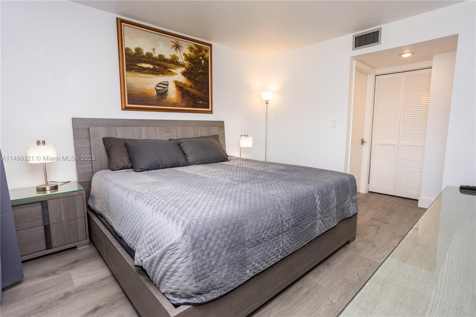 A bedroom features a gray bed, matching nightstand, wall art, and light wood-look flooring — 500 N Francisco St # 234, Clewiston FL 33440, CLEWISTON, FL