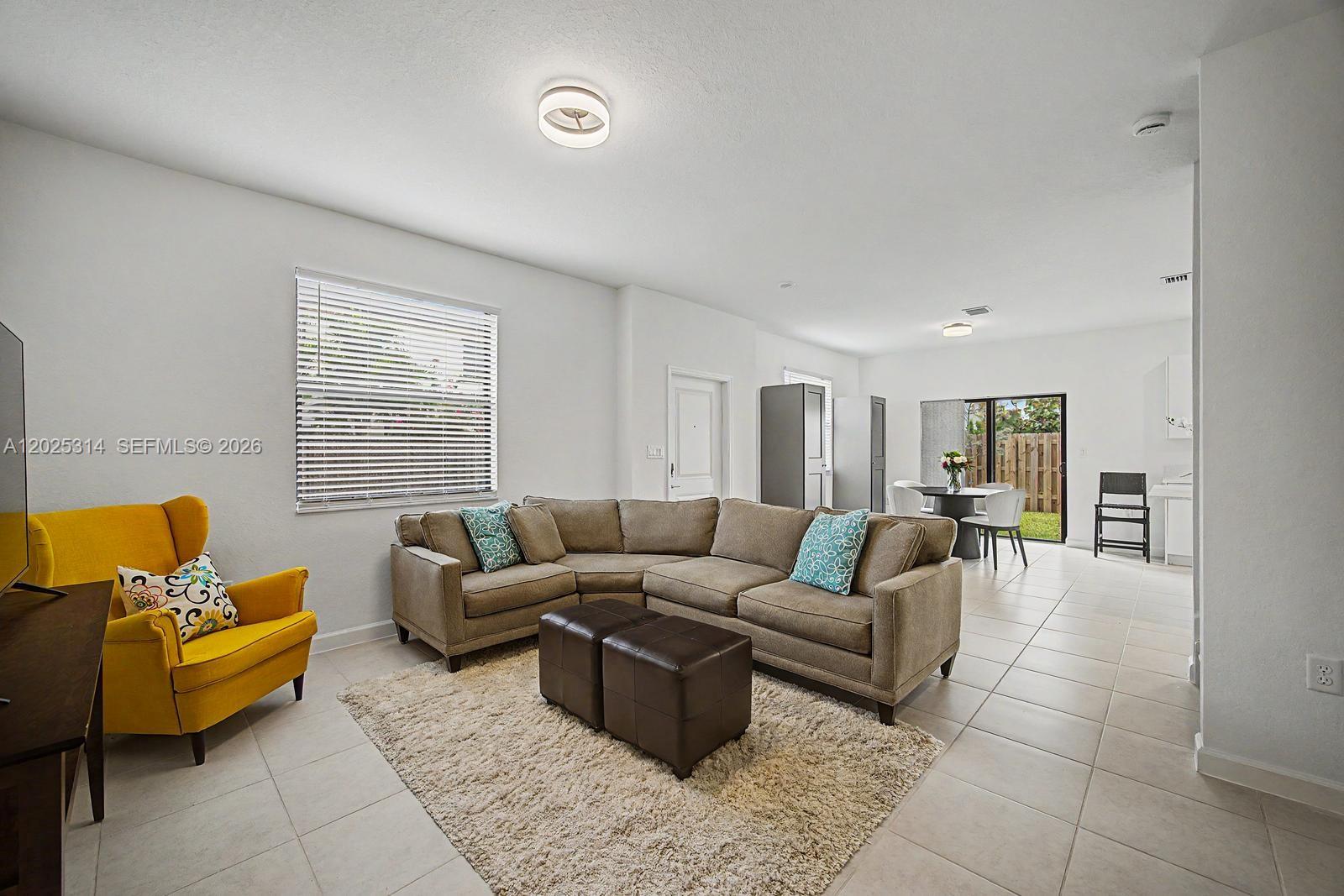A living room with a sectional sofa, yellow armchair, and tile flooring — 13170 SW 232nd Ln, Miami FL 33032, MIAMI, FL