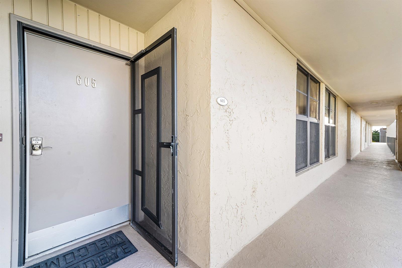 An exterior view of an apartment entrance with a screen door and a numbered door — 6 Royal Palm Way # 605, Boca Raton FL 33432, BOCA RATON, FL